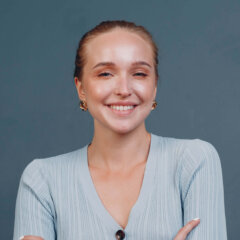 Portrait of young smiling european woman. Beautiful happy blonde girl wears t-shirt and looks at camera. Studio shoot isolated on blue background.